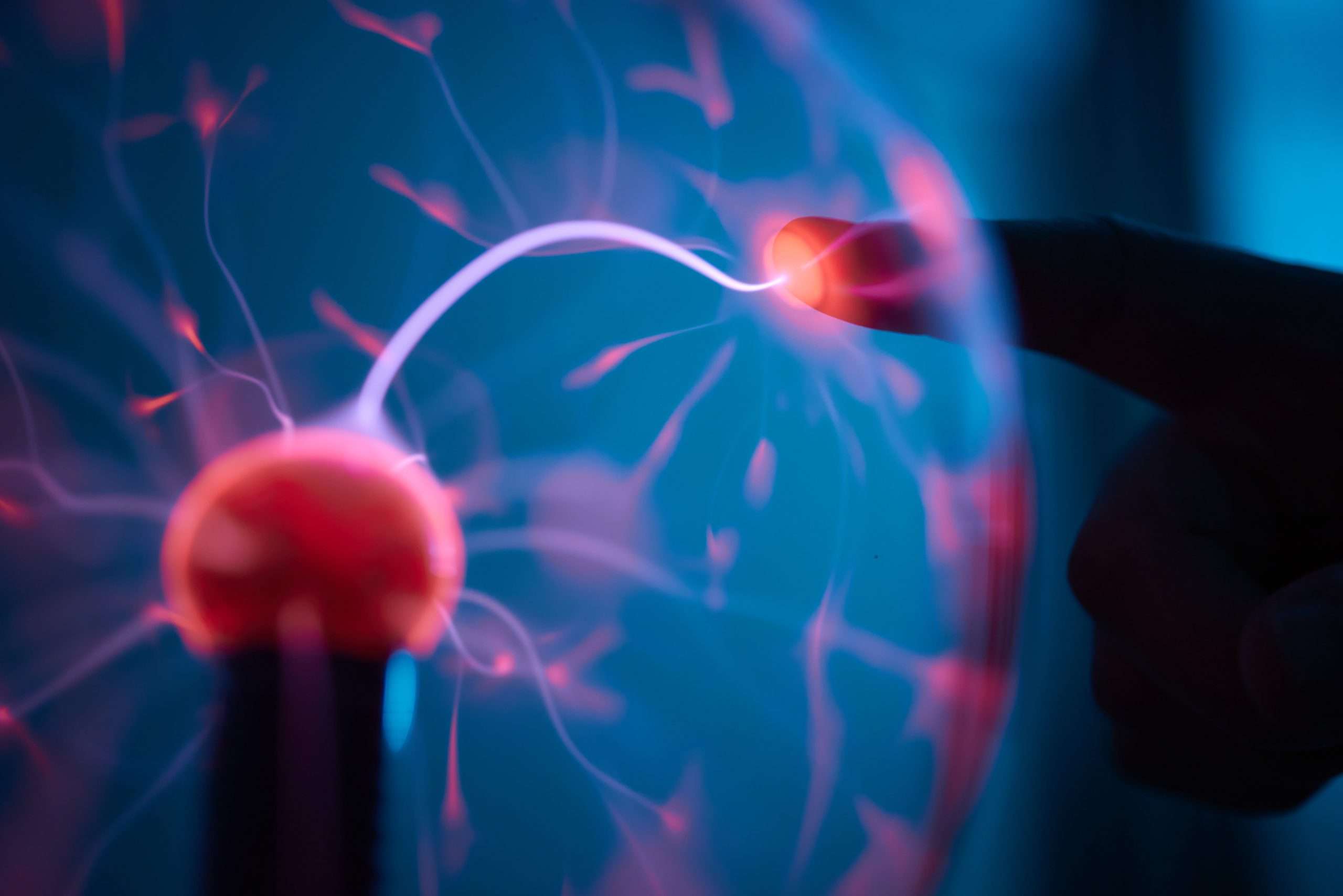 plasma ball. Hands holding plasma light ball. Plasma ball light ray science. Finger touching Plasma ball with smooth magenta blue flames. Electromagnetic Fields in a glass globe.